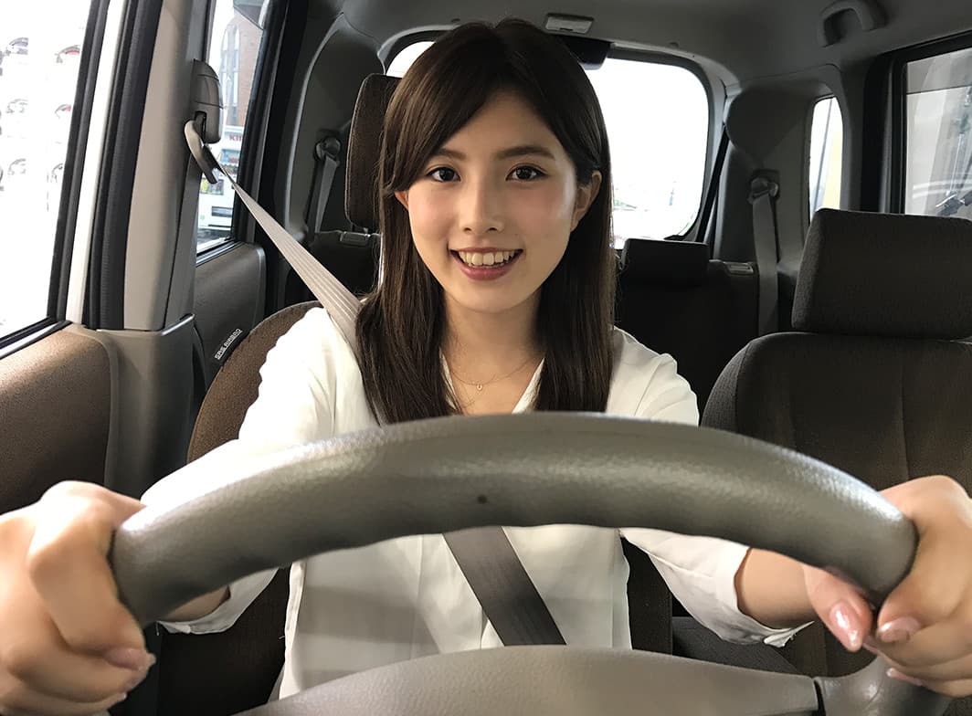 運転席でハンドルを握る笑顔の女性|タイヤ館